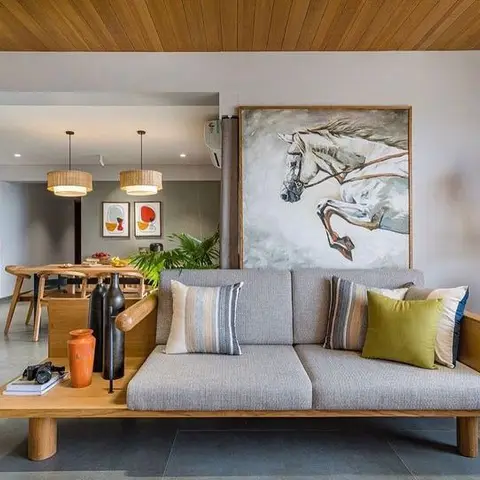Living room with a wood-framed grey sofa styled with striped and olive cushions beneath a large horse-themed wall painting
