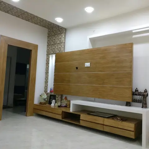 Living room with a wood-panel TV feature wall flanked by a 3D-textured tile border, and a matching low wood-and-white TV console styled with small idols.