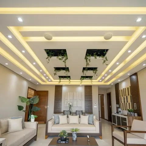 Living room with an elaborate multi-tier cove-lit false ceiling featuring geometric cutouts with trailing plants, cream sofas around a dark wood coffee table.