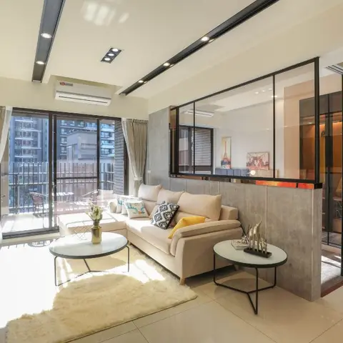 Living room with an L-shaped beige sectional sofa, two round coffee tables and a shaggy cream rug