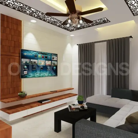 Living room with an L-shaped grey sectional sofa facing a wood-veneer TV console, under a cove-lit false ceiling with a laser-cut jaali insert framing the