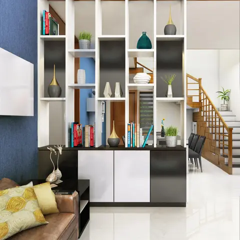Living room with an open shelving unit styled with vases and books acting as a room divider between the sofa area and a wooden staircase.