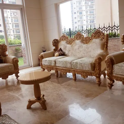 Living room with an ornately carved gold-leaf baroque-style sofa set on polished marble flooring facing a high-rise view