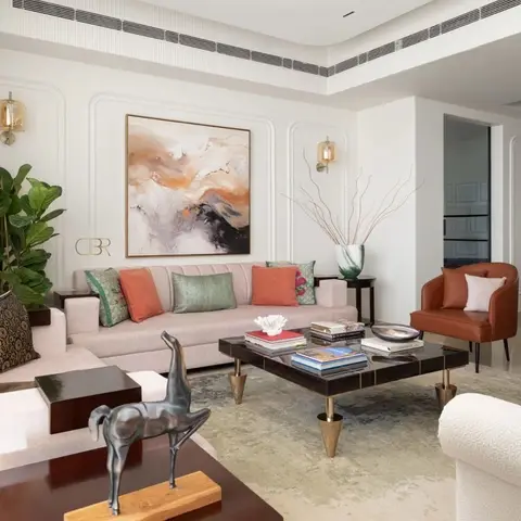 Living room with arched wall panel moulding behind a blush sofa styled with terracotta and sage cushions, a large abstract painting, brass wall sconces