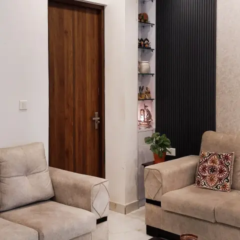 Living room with beige sofas around a black coffee table styled with copper vases, a fluted black display niche with curios