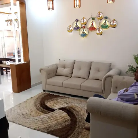 Living room with beige tufted chesterfield-style sofas, three cage-style pendant lights, an illuminated dancer-figurine wall art piece