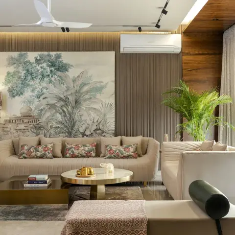 Living room with channel-tufted cream sofas around brass coffee tables, a large Indian palace garden mural on a ribbed panel wall