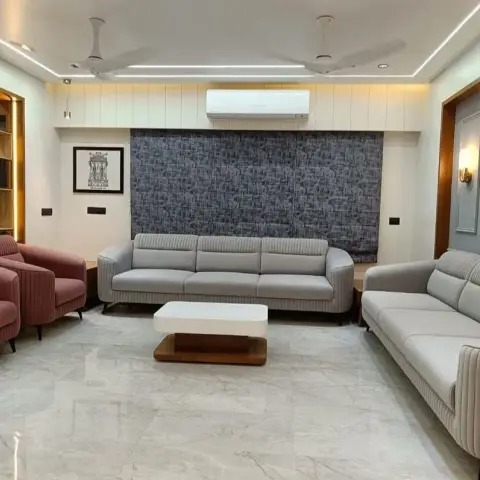Living room with channel-tufted grey sofas and dusty-rose armchairs facing a charcoal woven fabric accent wall