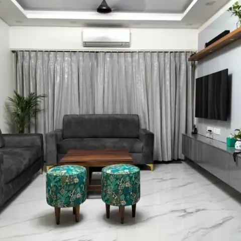 Living room with charcoal grey sofas around a wood coffee table and floral-print ottomans