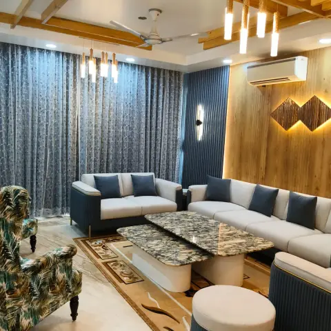 Living room with cream and navy sofas around twin figured-marble coffee tables, a wood-plank feature wall carrying a backlit chevron motif beside a fluted navy