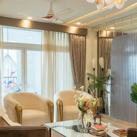 Living room with cream shearling-upholstered armchairs on gold clawed legs, a fluted grey wall panel flanked by mirrored wall segments