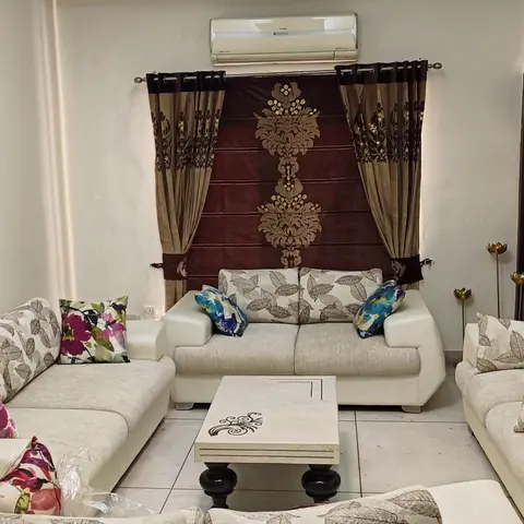 Living room with cream sofas and floral-print cushions arranged around a stone-inlay coffee table