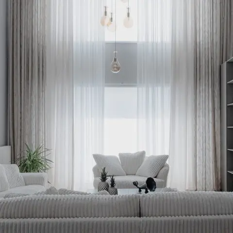 Living room with floor-to-ceiling sheer curtains, a cluster of amber glass pendant lights, and ribbed cream corduroy sofas styled with pineapple ornaments.