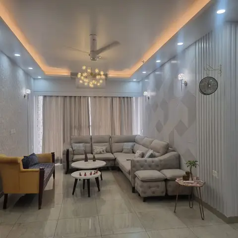 Living room with fluted wall panelling on both side walls, a warm cove-lit false ceiling, a sputnik-style chandelier