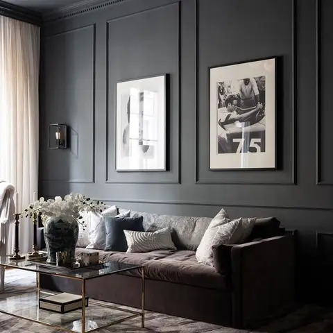 Living room with full-height dark grey wall panelling, a black-and-white art gallery, a brown velvet sofa