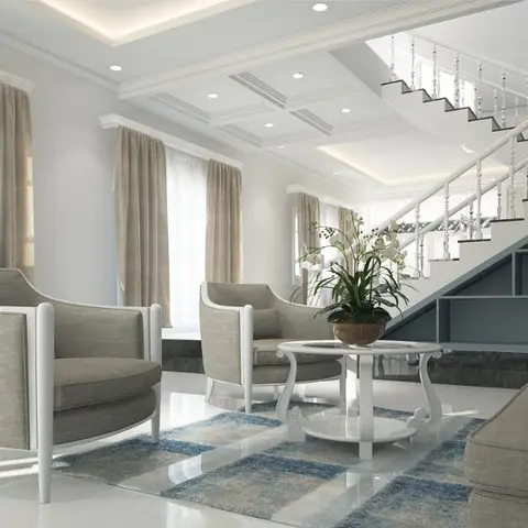 Living room with grey cabriole-leg armchairs and a round white coffee table beneath a staircase with under-stair storage.