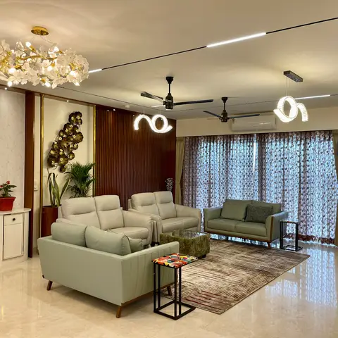 Living room with mint-green leather sofas, a fluted wood-and-brass panel wall featuring a metal leaf sculpture, and a floral chandelier over a patterned rug.