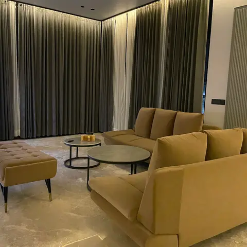Living room with mustard velvet sofas, a tufted bench with brass-capped legs, round nesting marble-top coffee tables