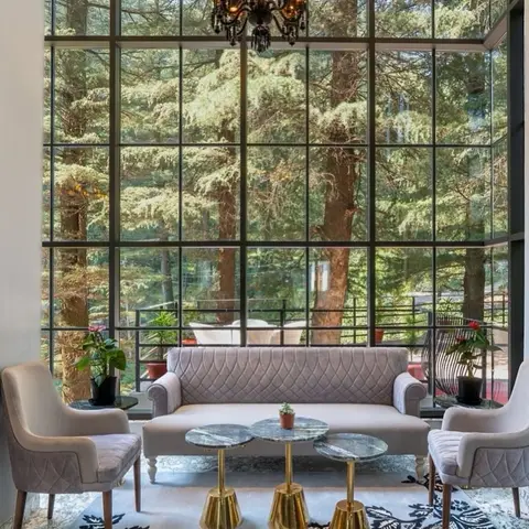 Living room with quilted mauve sofa and armchairs facing three round marble-and-brass side tables