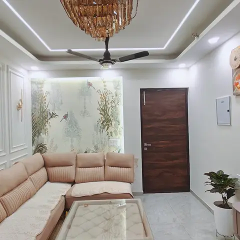 Living room with raised-panel wall moulding, a floral bird-print wallpaper feature wall, a crystal chandelier over a cove-lit ceiling