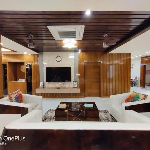 Living room with ribbed wood-panelled ceiling and walls, a floating TV console beneath a marble accent clock panel, curved white sofas