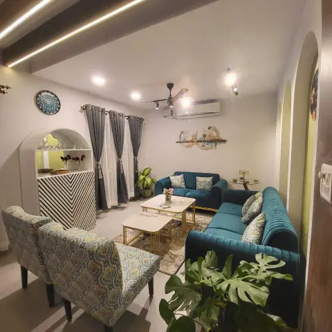 Living room with teal channel-tufted sofas around a nested gold-frame marble coffee table, patterned armchairs