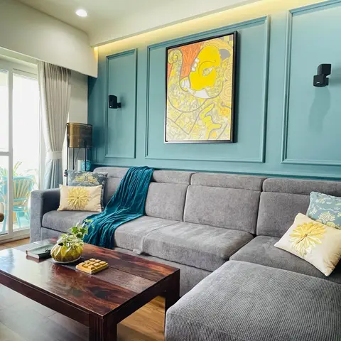 Living room with teal moulded wall panelling and a framed abstract art print behind a grey corner sectional sofa.