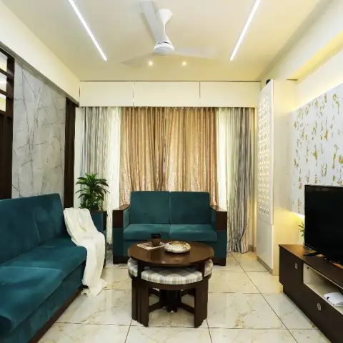 Living room with teal velvet sofas around a round wood coffee table with nesting stools, a gold-spatter textured accent wall behind the TV unit