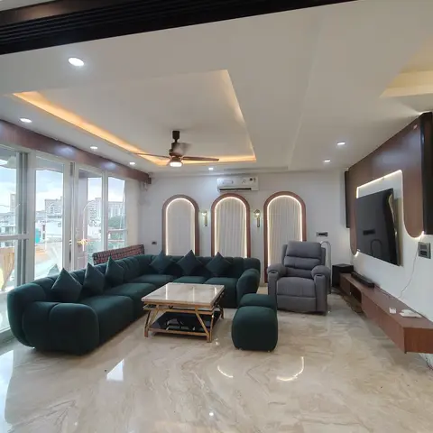 Living room with three arched, backlit wall niches, a glossy marble floor, a floating wood TV console, and a curved emerald sofa with a marble coffee table.