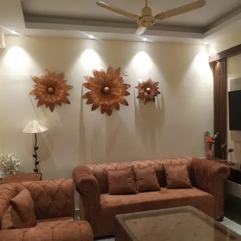 Living room with tufted rust-brown chesterfield sofas facing a fluted-panel TV console under a cove-lit stepped ceiling