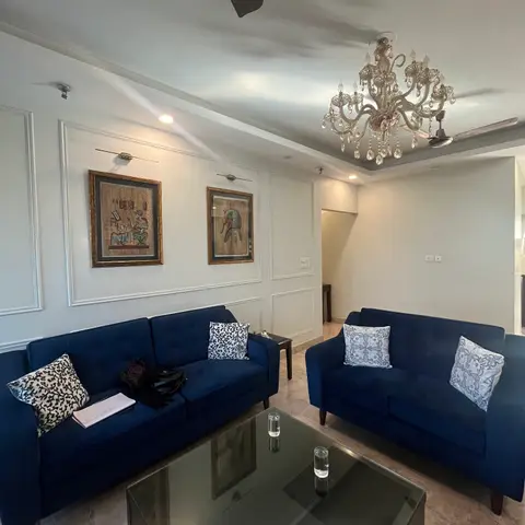 Living room with wainscot-style wall panelling, framed Egyptian papyrus art, navy velvet sofas with block-print cushions