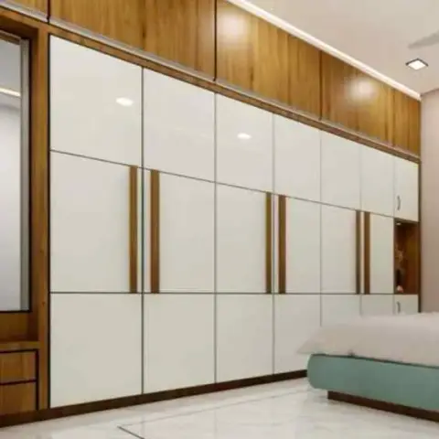 Long bedroom wardrobe wall in ivory gloss shutters split by teak-veneer handle grooves under a teak loft band lit from below