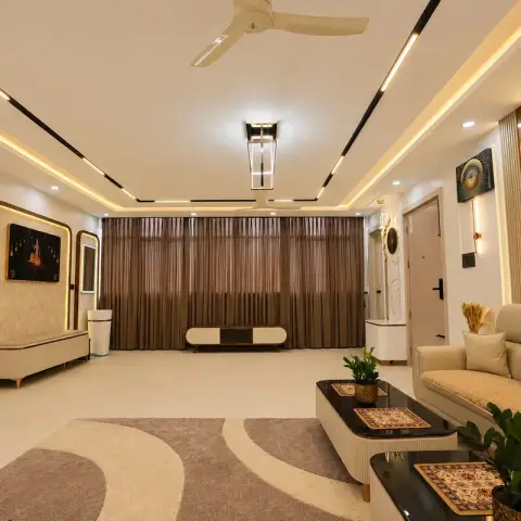 Long cream living room with a quilted leatherette sofa, two curved black-top tables on a swirl-cut carpet