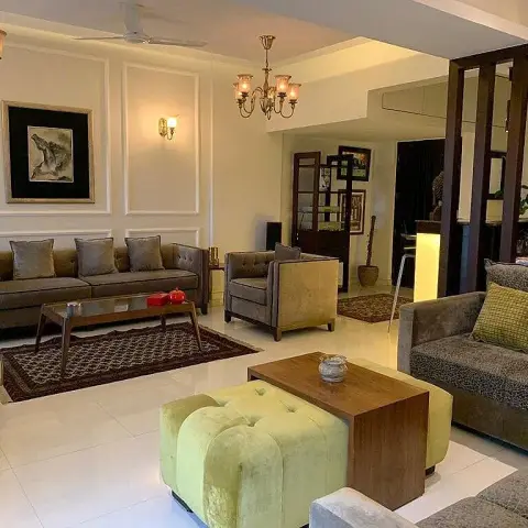 Long living room holding two seating groups - grey-brown velvet sofas with olive cushions