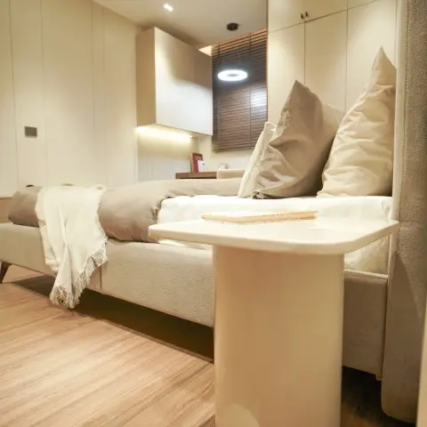 Low, close view across a cream upholstered bed to a floor-to-ceiling ivory wardrobe run