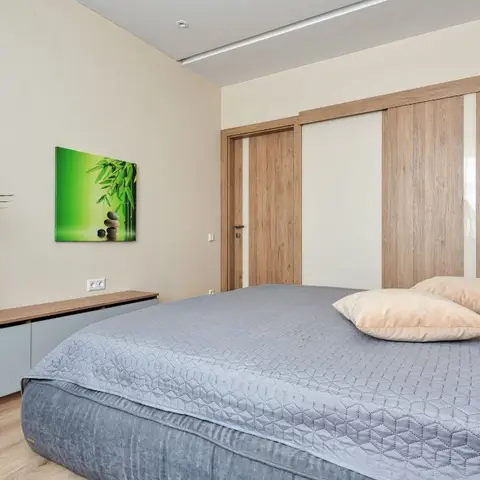 Low grey platform bed with a quilted honeycomb cover, running alongside a wall-hung oak-and-grey console, under a cluster of black