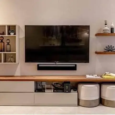 Low, long TV console with a teak top and white drawer fronts, two ceramic drum stools pushed underneath it