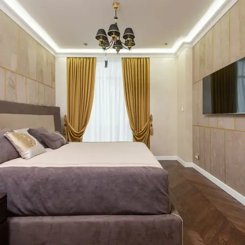 Luxury master bedroom with mauve velvet upholstered bed, gold-lined marble-effect wall panelling