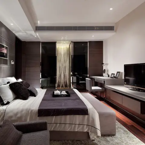Luxury master bedroom with quilted grey leather-look wall panelling, a bench at the foot of the bed, a dark wood-floor TV console area