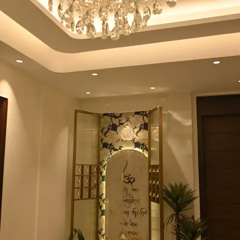 Mandir niche with reeded-glass and brass shutters hung with rows of little bells, opening onto a backlit marble arch carved with the Gayatri mantra