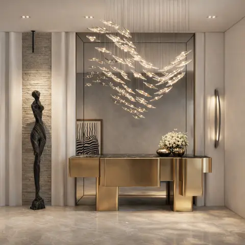 Marble-floored entrance foyer with a sculptural bird-shaped pendant light cluster above a brass geometric console table and a tall bronze standing figure