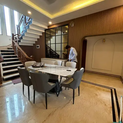 Marble-top dining table with grey leatherette chairs on beige marble laid with a black inlay border