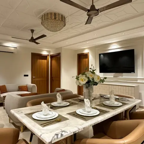 Marble-topped six-seater laid with jute placemats and folded napkins under a crystal drum chandelier, tan leather chairs around it
