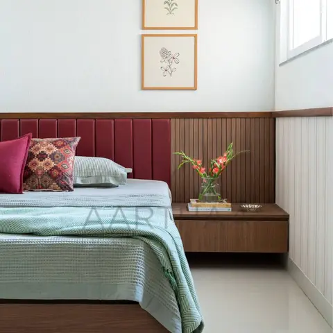Maroon channel-tufted leather headboard set against a teak fluted dado that turns the corner into a floating walnut bedside
