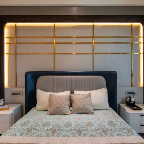 Master bed backed by a brass lattice grid over a textured cream panel, edge-lit inside a dark wood-veneer frame