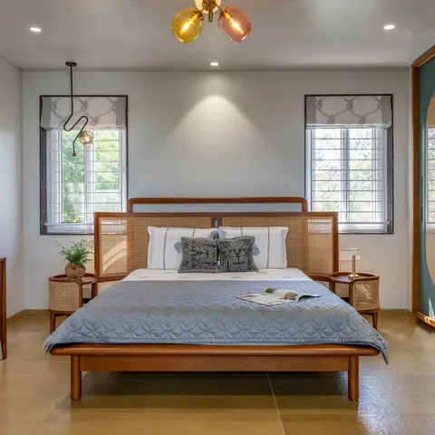 Master bedroom in a mid-century style with a cane-panelled wood bed, matching cane bedside tables, a teal wardrobe with rattan inset doors