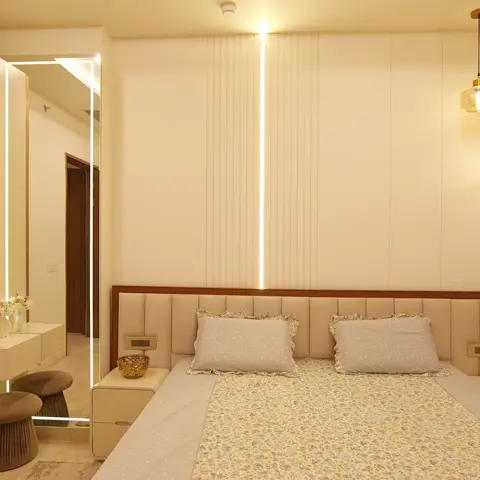 Master bedroom with a backlit fluted panel headboard wall lit by a vertical LED strip, amber glass pendant lights, and a mirrored dressing nook with stools.