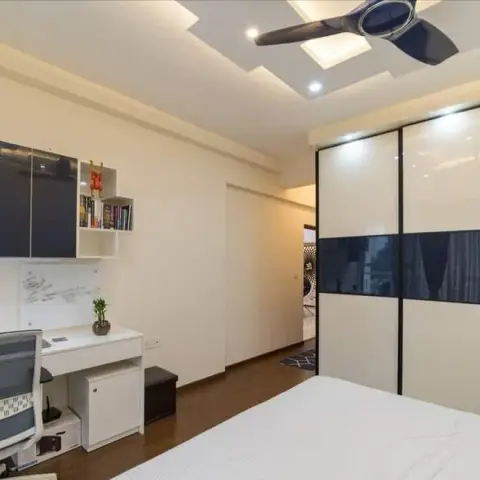 Master bedroom with a black-and-cream glossy sliding wardrobe, a built-in study desk with an open bookshelf