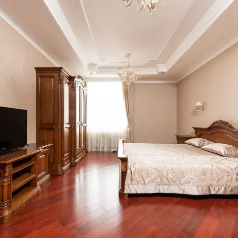 Master bedroom with a carved dark-wood bed and matching nightstands, an ornate wardrobe and TV console in the same finish, damask wallpaper