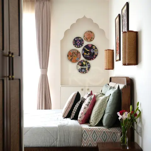 Master bedroom with a carved jharokha-shaped wall niche displaying five decorative plates